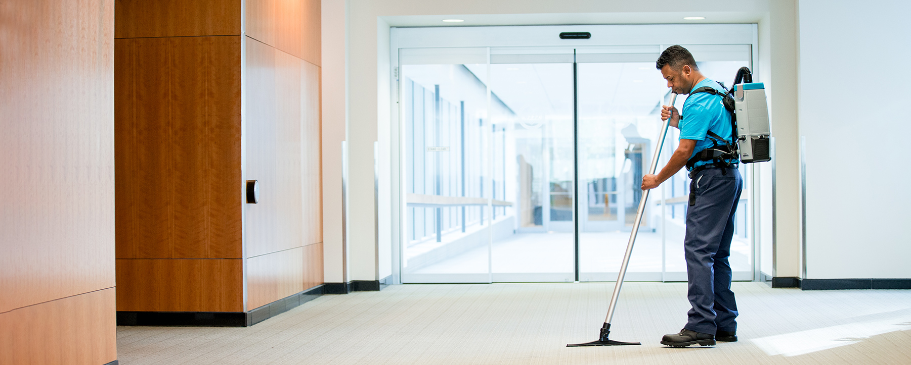 Mac's janitorial company employee cleaning the hallway of corporate office facility