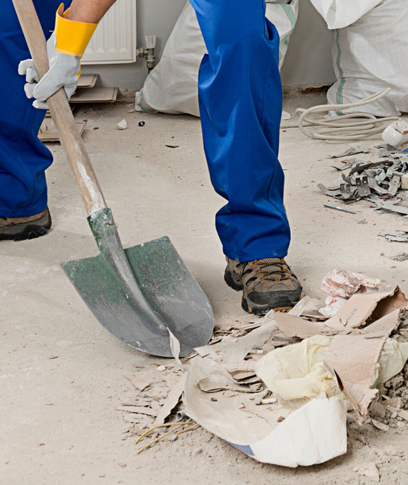 Construction Cleaning service project with Mac's janitor shoveling construction materials for trash