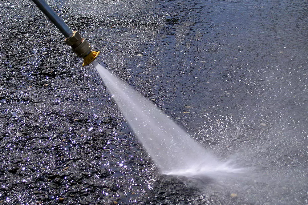 Power washer spraying on sidewalk surface cleaning walkway