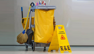 Cleaning cart with mops, brooms, spray bottles and caution floor sign
