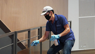 Cleaner spraying and wiping down railing in corporate office facility