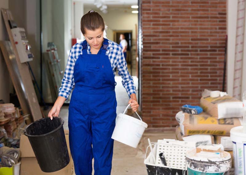 Woman deep cleaning back room area with construction materials