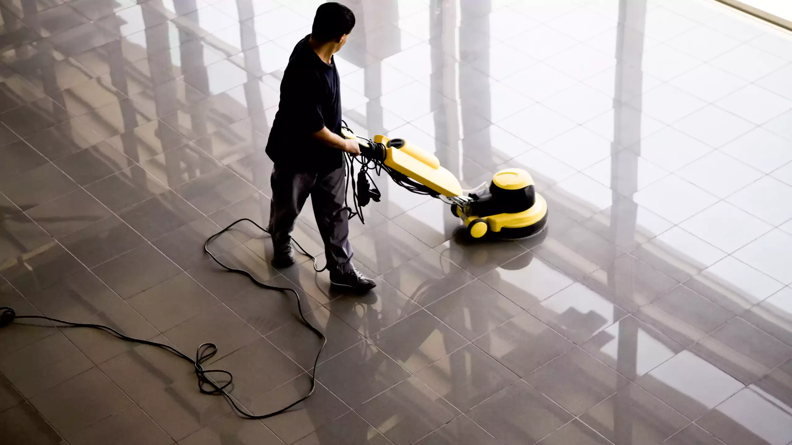 Cleaner buffing the floor in a corporate office building lobby