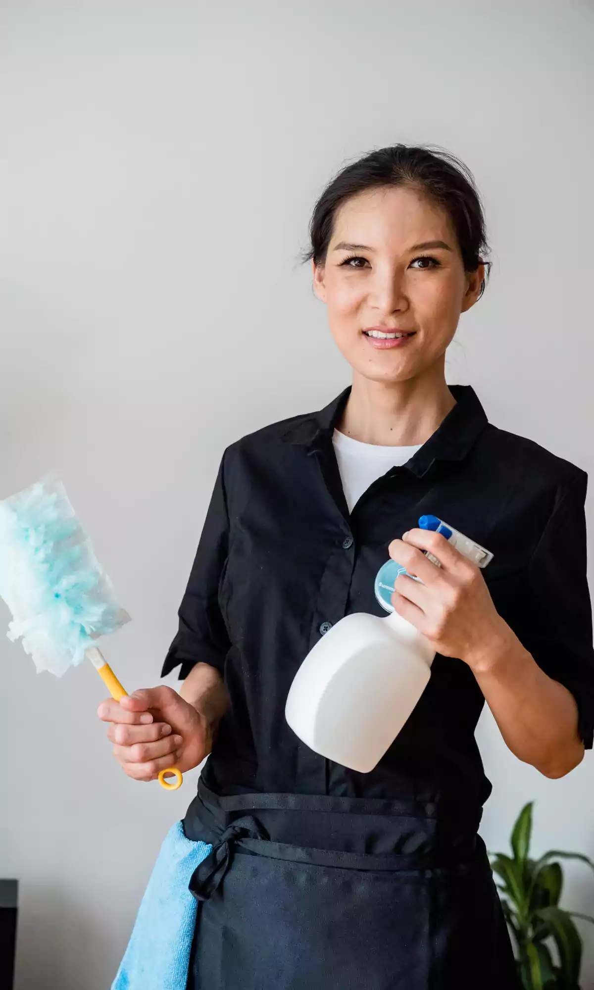 Woman cleaner and janitor holding spray bottle and duster