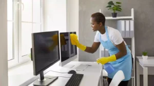 Woman cleaning computer monitors in office