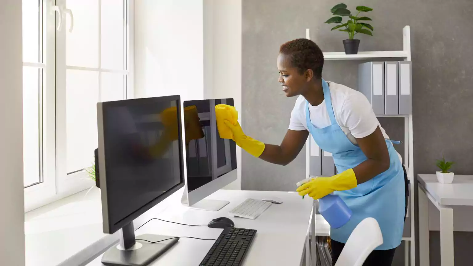 Woman cleaning computer monitors in office