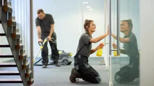 Commercial cleaning company employees vacuuming and washing windows.