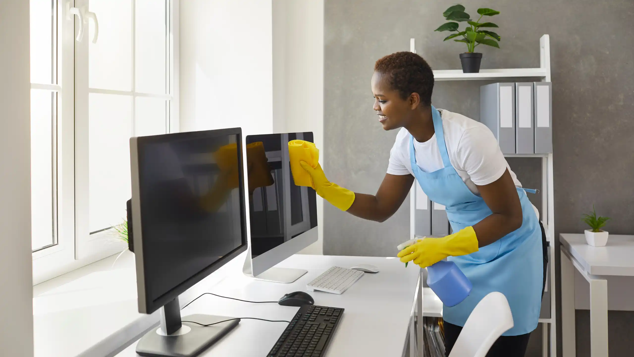 Cleaning Service cleaning office with woman wiping flat screen computer monitors