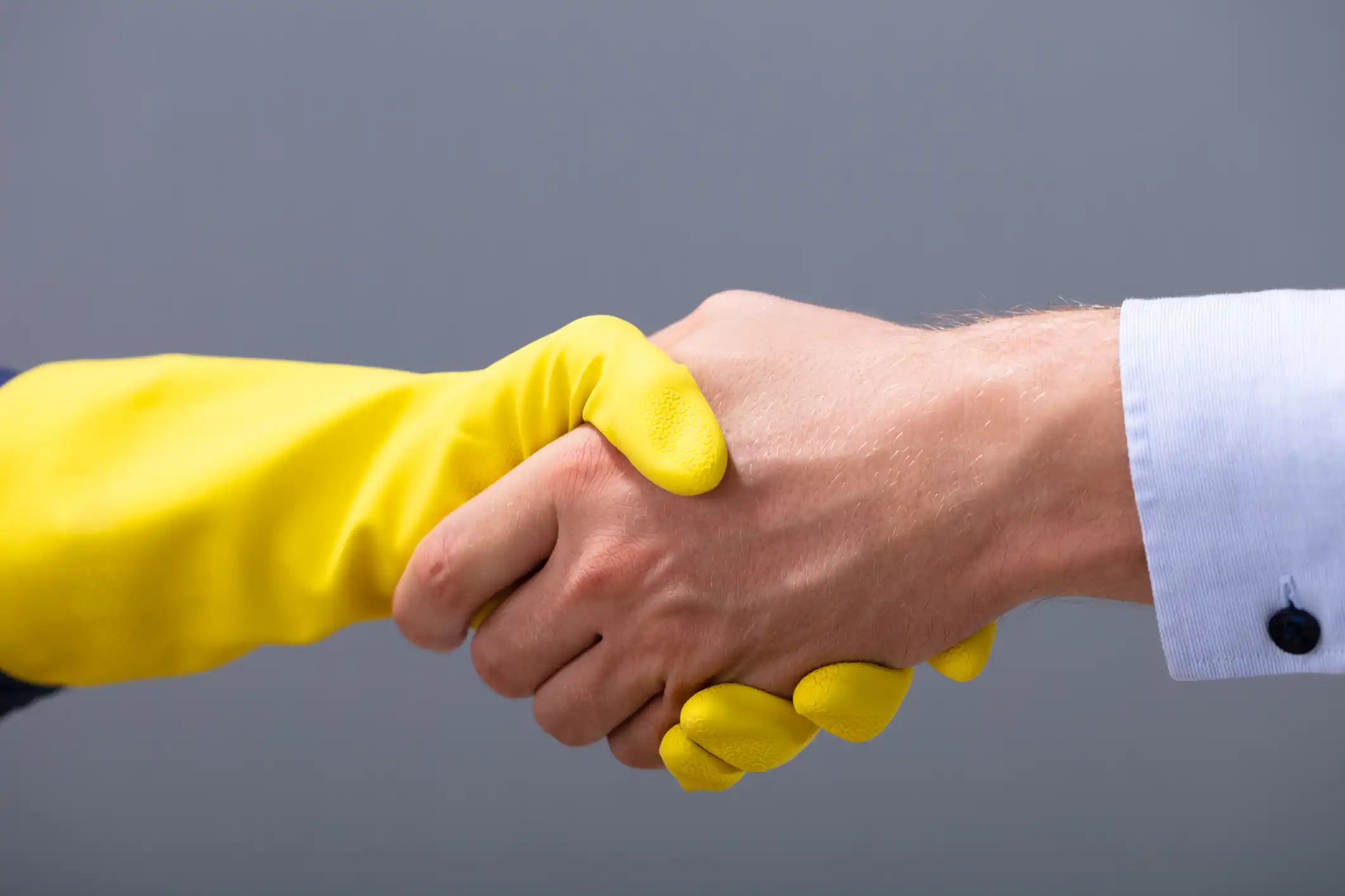 Two hand shaking one with yellow glove and the other bare handed